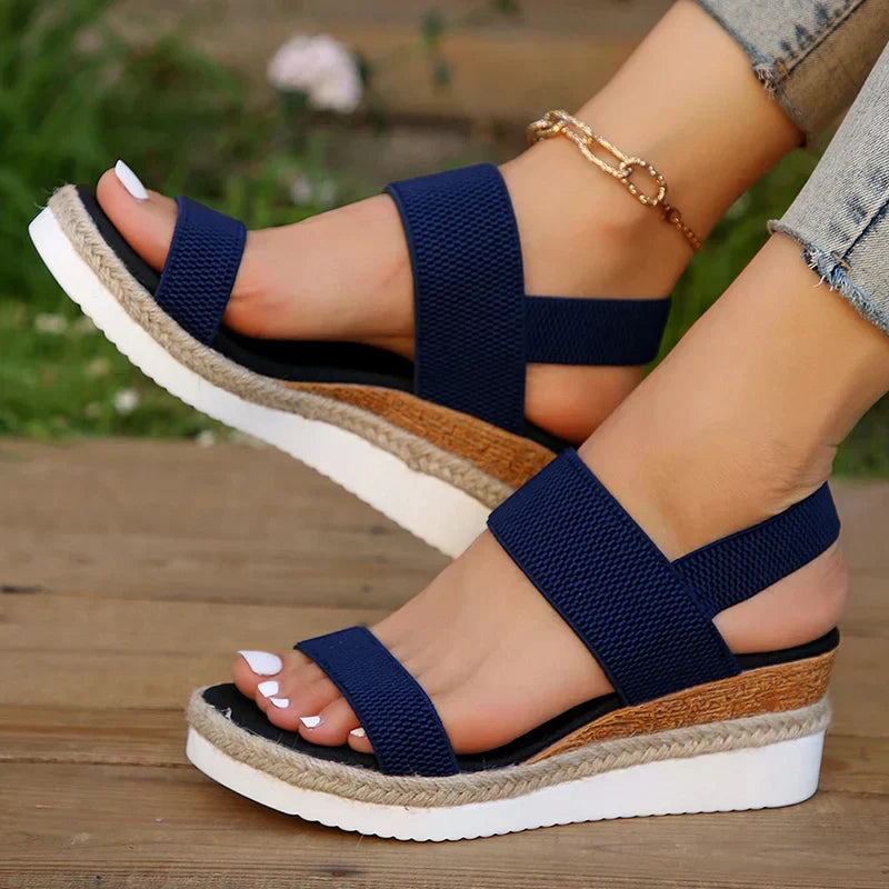 Woman modeling soft sole sandals on a plain background for easy everyday outfits.